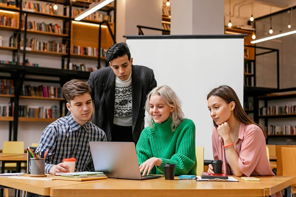 people in a library looking at laptop together