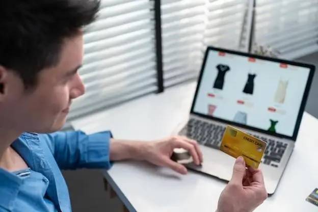 A man shopping online on his laptop, focused on the screen with a thoughtful expression.