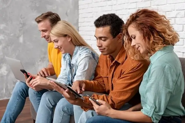 Four individuals seated on a couch, each focused on their smartphones, creating a scene of modern connectivity.