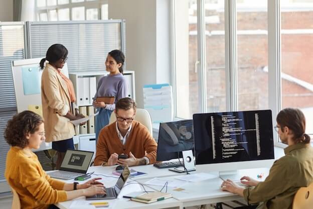 A diverse group of professionals collaborating in a modern office environment, focused on their tasks and discussions.