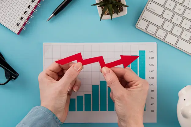 Hands of a businessman holding a red arrow on a paper with a graph, symbolizing growth and success.