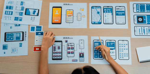 A designer focused on creating a mobile application interface, surrounded by sketches and digital tools.